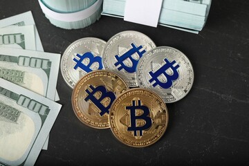 Cryptocurrency. Bitcoins and dollar banknotes on black table, flat lay
