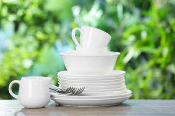 Different clean dishes on wooden table against blurred green background