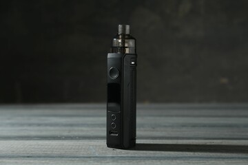 One electronic smoking device on grey wooden table against dark background, closeup