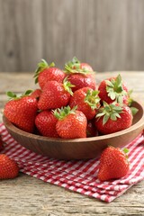 Fresh ripe strawberries in bowl on wooden table, closeup