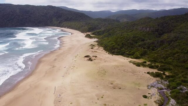 Drone shot of Pacific waves hitting Rada Ranu beach, Chile. Untouched nature, forest and ocean meet in this cinematic coastal view