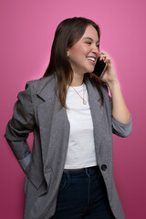 Young woman using smartphone in studio portrait with pink background