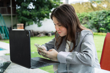 Young woman working remotely with tablet and smartphone outdoors