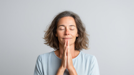 Peaceful woman with closed eyes practicing mindfulness meditation in prayer pose for mental wellness
