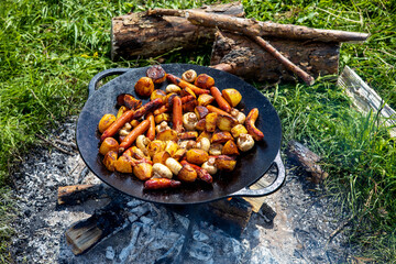 Champignons, grilled sausages and potatoes cooked on a cast iron saj. Picnic in the nature in...