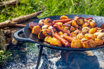 Champignons, grilled sausages and potatoes cooked on a cast iron saj. Picnic in the nature in...