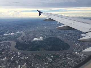 Aerial view of Bangkok, Thailand from airplane window, featuring Chao Phraya River, lush Bang...