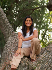 Young Hispanic Teen Girl Sitting In Tree Smiling
