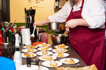 Chef decorating cream puffs with chocolate.
