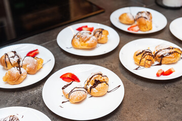 Cream puffs with chocolate drizzle and strawberries.