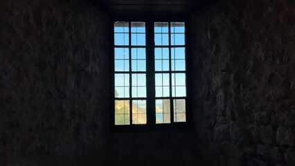 Fototapeta premium A beautifully crafted window frame offers a picturesque view of nature beyond a historic stone wall