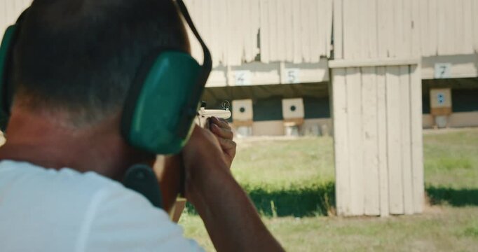 Man aiming and firing wooden rifle at targets on a sunny shooting range
