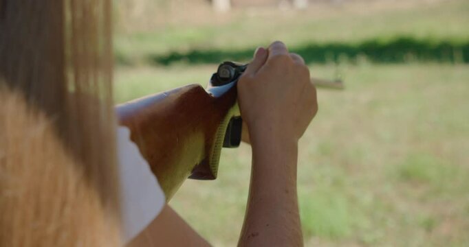 Person ejecting spent cartridge from bolt-action rifle during target practice outdoors
