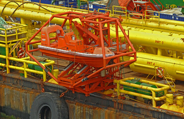 Escape vessel and work boat rests in cradle attached to a huge offshore derrick barge