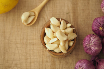 Fresh garlic cloves and red onions on wooden surface