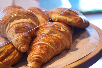 Croissants arranged on a wooden platter with glass cover