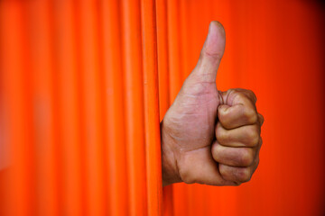 Hand Giving Thumbs Up Gesture Behind Vertical Orange Bars