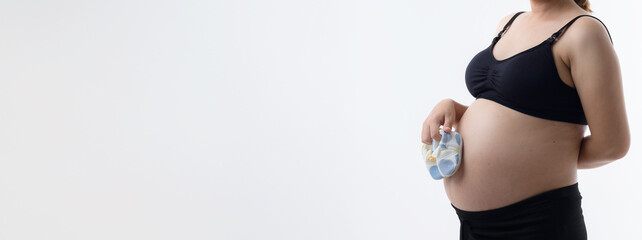 Beautiful pregnant woman hugging her tummy at home studio.