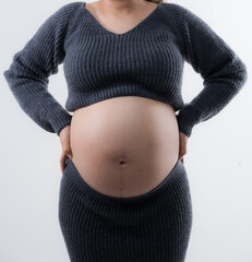 Beautiful pregnant woman hugging her tummy at home studio.