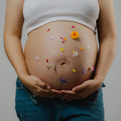 Beautiful pregnant woman hugging her tummy at home studio.