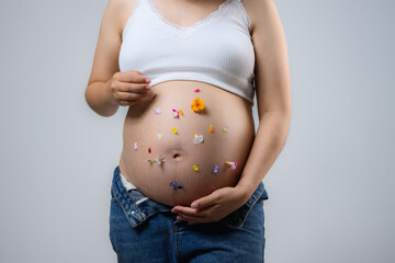 Beautiful pregnant woman hugging her tummy at home studio.