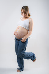 Beautiful pregnant woman hugging her tummy at home studio.