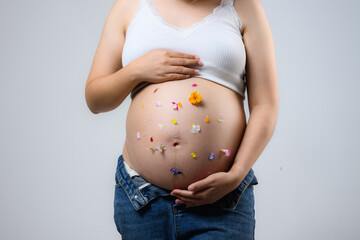 Beautiful pregnant woman hugging her tummy at home studio.