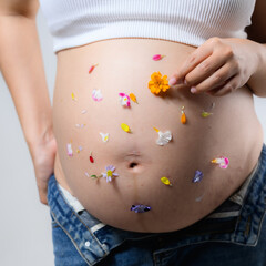 Beautiful pregnant woman hugging her tummy at home studio.