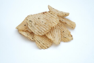 Close-up of a pile of crispy, ridged potato chips lightly seasoned with herbs, perfect for snacking.