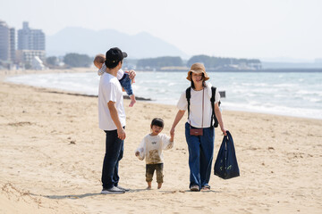 In early March, a 6-month-old baby, a 3-year-old girl, and their Japanese parents in their 30s walk together on a sandy beach by the sea. A springtime moment filled with warmth and connection.