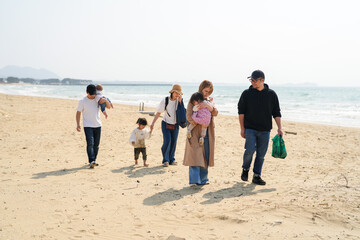 In early March, Japanese families enjoy the beach together: a 6-month-old baby, a 1-year-old girl, a 3-year-old girl, and parents in their 30s. A cheerful springtime scene filled with warmth and joy.