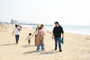In early March, Japanese families enjoy the beach together: a 6-month-old baby, a 1-year-old girl, a 3-year-old girl, and parents in their 30s. A cheerful springtime scene filled with warmth and joy.