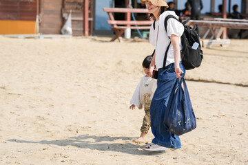 In early March, a 3-year-old Japanese girl and her mother in her 30s enjoy a happy moment together on a sandy beach by the sea. A cheerful springtime scene filled with smiles and warm connection.