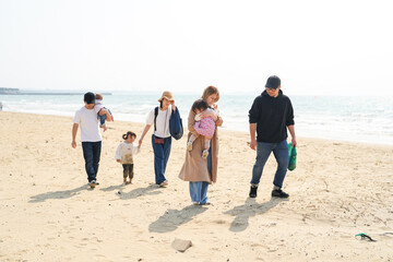 In early March, Japanese families enjoy the beach together: a 6-month-old baby, a 1-year-old girl, a 3-year-old girl, and parents in their 30s. A cheerful springtime scene filled with warmth and joy.