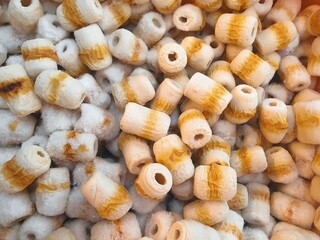 Close-up of numerous cylindrical, subtly striped, off-white and tan food items.