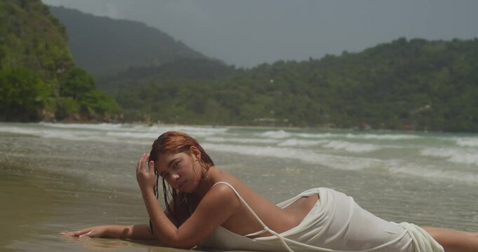 A young girl in a white beach dress finds peace laying on Trinidad's golden sand beach
