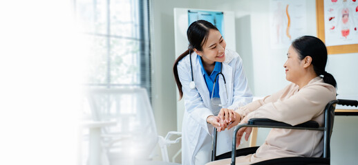 Female doctor holding the hand of a patient in a wheelchair,providing comfort and emotional support...