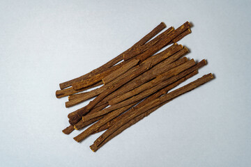 Flat lay of dried licorice roots on white background. Natural herbal remedy and ingredient used in traditional medicine and candy production.