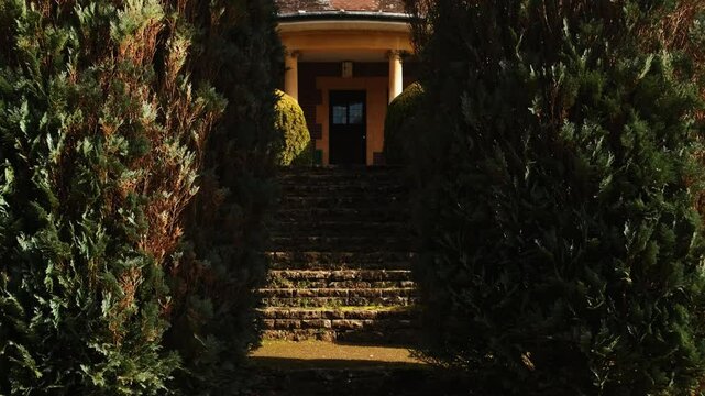 Tilt shot of a beautiful garden with leading stairs up to a mansion entrance.