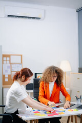 Two female designers brainstorming color palettes in a modern office. Creative teamwork, branding,...