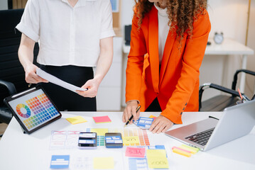 Closeup of UX UI designers planning mobile layouts with wireframes, color swatches, sticky notes,...