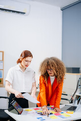 Two female designers brainstorming color palettes in a modern office. Creative teamwork, branding,...