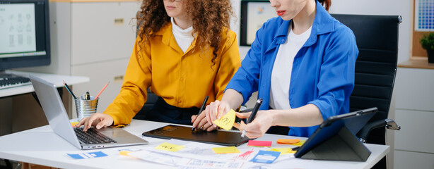 Closeup of UX UI designers planning mobile layouts with wireframes, color swatches, sticky notes,...