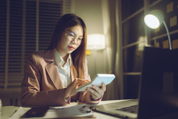 Professional young woman wearing glasses and blazer working with her laptop at a tidy desk,...