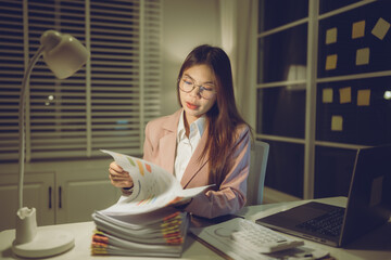 Professional young woman wearing glasses and blazer working with her laptop at a tidy desk,...