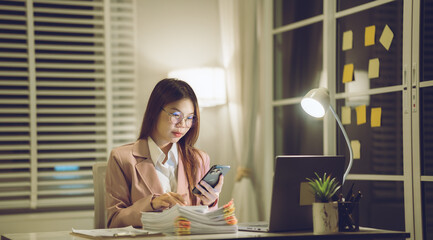 Professional young woman wearing glasses and blazer working with her laptop at a tidy desk,...