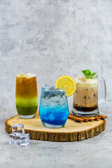 A trio of refreshing drinks: coffee matcha latte, vibrant blue squash with basil seeds, and creamy choco banana with mint. Perfect for café menus and creative beverage photography.
