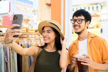 Happy tourists couple taking selfie in a clothing store