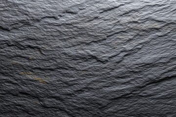 A closeup of a textured dark gray slate surface with subtle variations in tone and rugged layered patterns