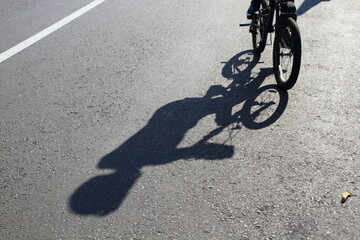 Shadow of a man riding his bicycle on the street.